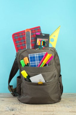 Sırt çantasında farklı renkte kırtasiye malzemeleri var. Açık mavi arkaplan. Okula geri dön.