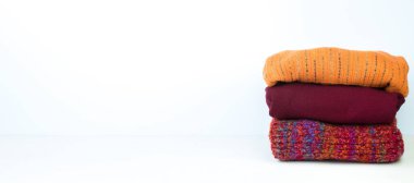 Yünlü yün kazaklar. Bir demet örülmüş kış, arka planda sonbahar kıyafetleri, süveterler, örgü giysiler, yazı için yer. Pankart