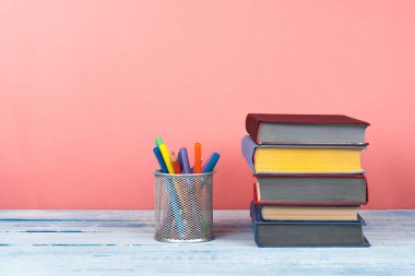 Kitap istifleme. Açık bir kitap, ahşap masa ve kırmızı arka plan üzerine ciltli kitaplar. Okula dönelim. Metin için alanı kopyala