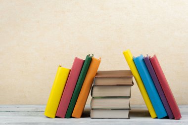 Kitap istifleme. Açık kitap, ahşap masa ve mavi arka plan üzerine ciltli kitaplar. Okula dönelim. Metin için alanı kopyala