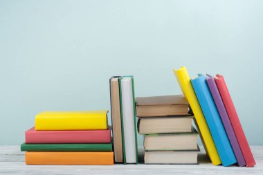 Kitap istifleme. Açık kitap, ahşap masa ve mavi arka plan üzerine ciltli kitaplar. Okula dönelim. Metin için alanı kopyala