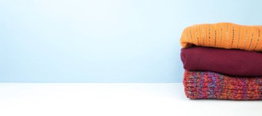 Yünlü yün kazaklar. Kış örgüsü, mavi arka planda sonbahar kıyafetleri, kazaklar, örgü giysiler, yazı için yer. Pankart.