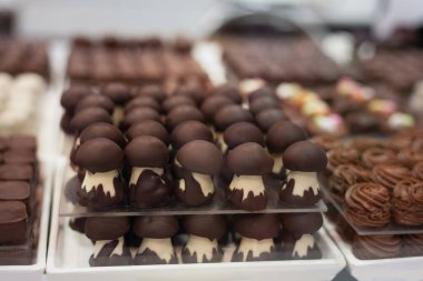 Şenlikli beyaz masada siyah ve kahverengi çikolatadan yapılmış lezzetli tatlılar ve kurabiyeler.