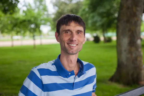 Neşeli, orta yaşlı, neşeli bir adam. Dışarıda güneşli bir günde.