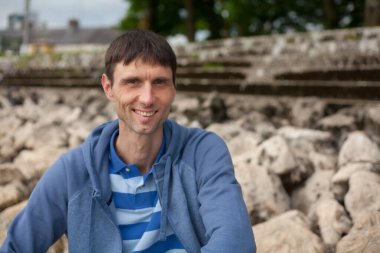 Neşeli, orta yaşlı, neşeli bir adam. Dışarıda güneşli bir günde.