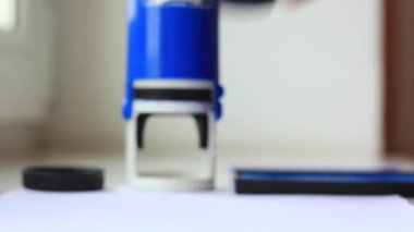 Bir adam elini mürekkebe batırır ve mühür basar..