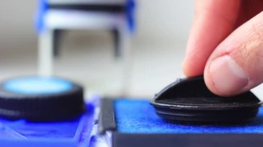 Erkek eli mürekkep kaplamasında pul ıslatıyor.