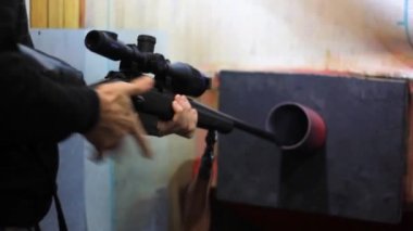 Erkek eller bir silah tutar - bir tüfek ve bir kurşun yakalayıcıya ateş eder..