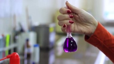 Bir kadın eli test tüpünde farklı bileşimlerin bileşenlerini karıştırır..