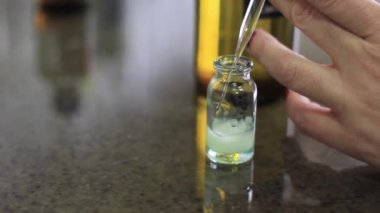Bir kadın, kimyasal çözeltileri karıştırmak için şişeye sıvı döker..