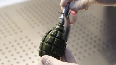 Lastik eldivenli bir erkek el bombası çevirir..