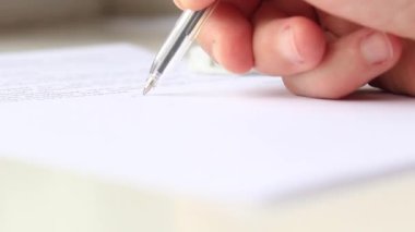 Bir adam bir belgeyi kalemle imzalar ve pul yapıştırır..