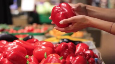 Female hands choose red pepper in a supermarket.