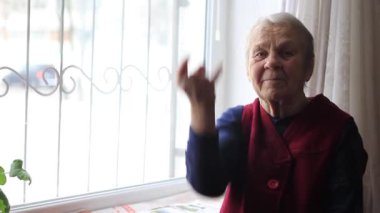 Elderly woman, grandmother shows hand gestures.