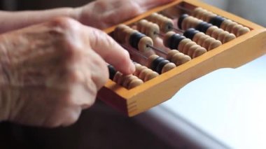 Elderly womans hand counts on vintage abacus.