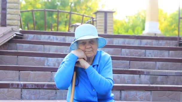 Μια Ηλικιωμένη Γυναίκα Μια Γιαγιά Μπλε Καπέλο Κάθεται Στα Σκαλιά — Αρχείο Βίντεο