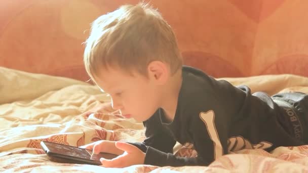 Μικρό Αγόρι Ξαπλωμένο Στον Καναπέ Παίζει Στο Τηλέφωνο — Αρχείο Βίντεο