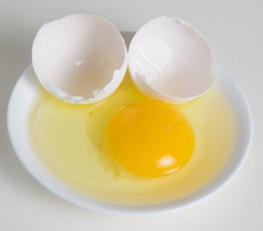 Bir tabakta yumurta sarısı ve kabuğu. Beyaz bir arkaplanda izole et..