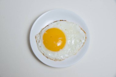 Beyaz plaka üzerinde kızarmış yumurta beyaz arka planda düz bir üst görünümde izole edilir.