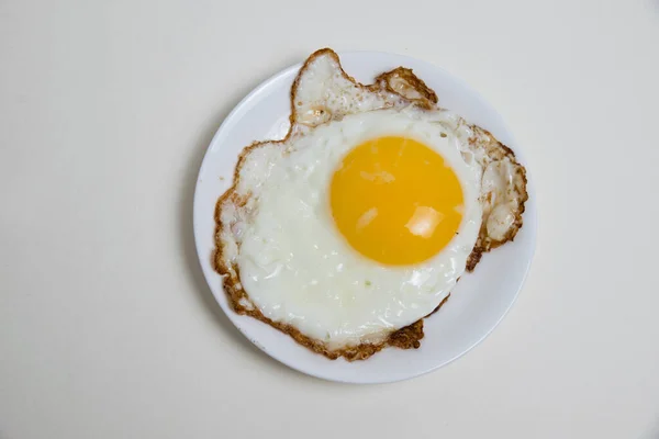 Fried egg on white plate isolate on white background. Concept of high prices for eggs and food.