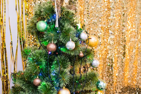 ボールとガーランドで飾られたクリスマスツリーは明るく光沢のある黄色の背景にあります 新年のお祝いのコンセプト — ストック写真