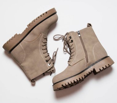 Beyaz arka planda bağcıkları olan gri kadın kış botları. Modern kadın modası kavramı.