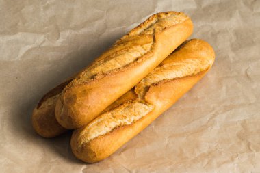 Delicious baguettes close-up, on baking paper. Concept of development of craft bakeries.