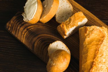 Delicious baguette with butter on a wooden cutting board close-up, flatlay.