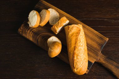 Appetizing baguette with butter on a wooden cutting board, flatlay.