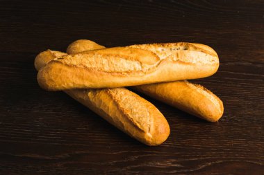 French baguettes with appetizing crusts on a wooden background close-up.