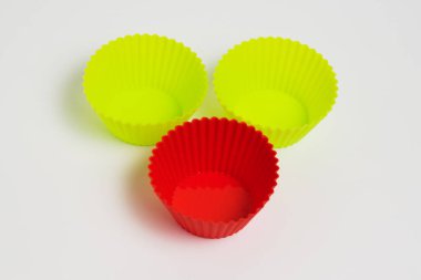Yellow and red silicone molds for baking a cupcake on a white background.