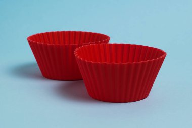 Red silicone molds for a cupcake on a soft blue paper background.