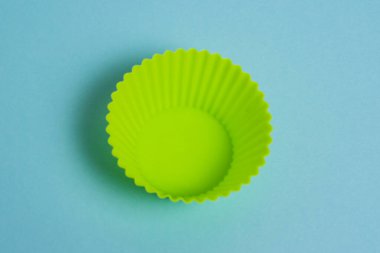 Yellow silicone mold for a cupcake on a light blue paper background.