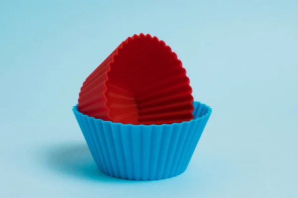 Blue and red silicone cupcake molds on a light blue paper background.