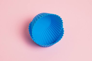 Blue silicone molds for cupcakes on a pink paper background.