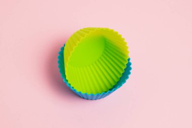 Yellow and blue silicone cupcake molds on a pink paper background.