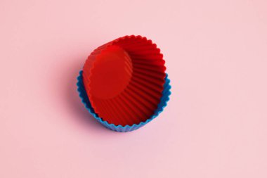 Red and blue silicone cupcake molds on a pink paper background.