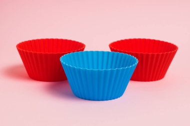 Red and blue silicone cupcake molds on a pink paper background.