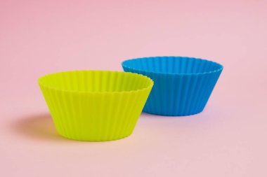 Blue and yellow silicone cupcake molds on a pink paper background.