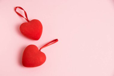 Valentine's Day celebration concept. Two red hearts on pink paper background with copy space, flatlay.