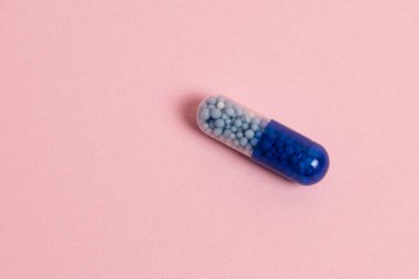 Pill macro on a pink background. The concept of improving the human body and protecting it from diseases