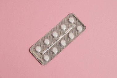 White pills in a blister on a pink paper background. Concept of treatment of diseases and support of the body in spring.