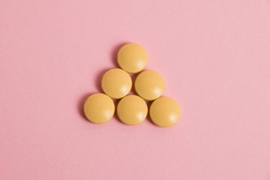 Yellow vitamins in pills on a pink paper background. Concept of immunity support in spring
