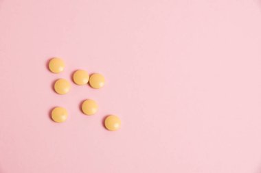 Yellow vitamins in pills on a pink paper background. Concept of immunity support in spring