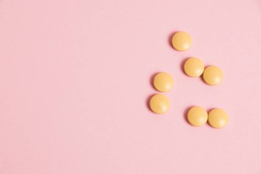 Yellow vitamins in pills on a pink paper background. Concept of immunity support in spring
