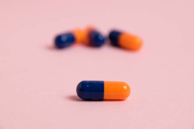 Multicolored pill on pink paper background with copy space, macro. Concept of treatment of covid 19 and colds