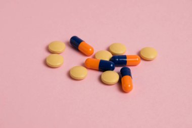Multicolored pills on pink paper background with copy space. Concept of covid 19 treatment and immunity support