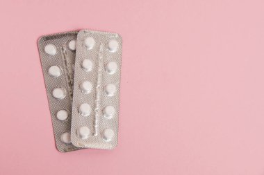 Flatlay, blisters with pills on pink paper background with place for text.