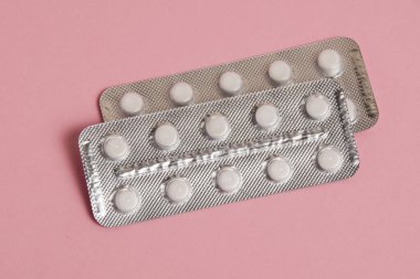 Blisters with pills on pink paper background with space for text.