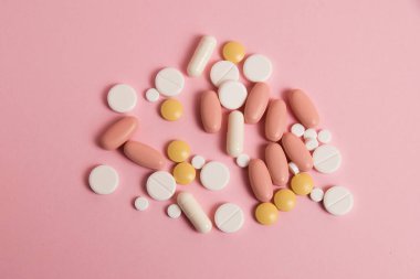 Flatlay, many different pills on a pink background.